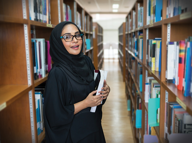 Teacher standing in library with a book in hand