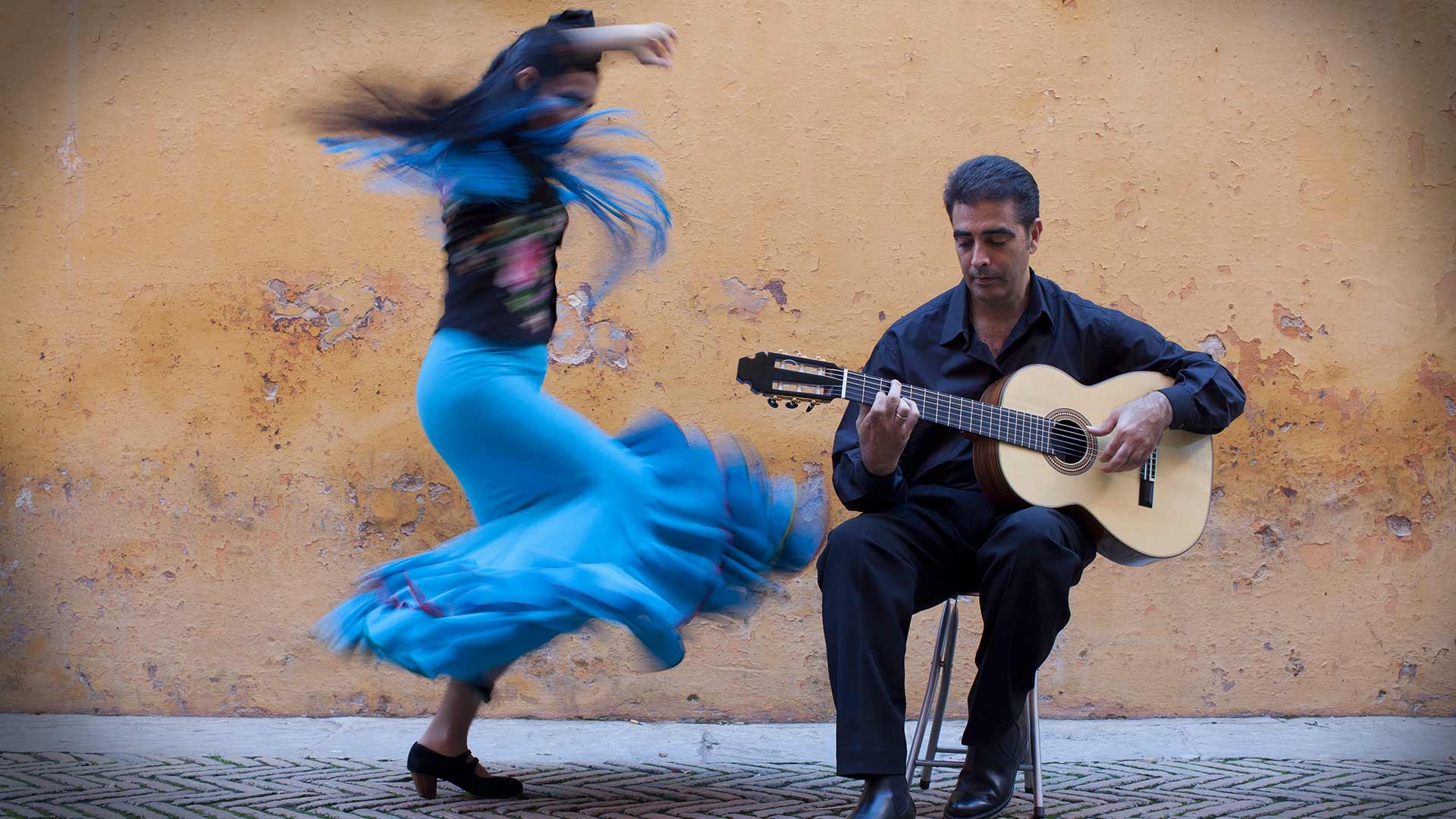 Woman dancing in the streets to a man playing guitar