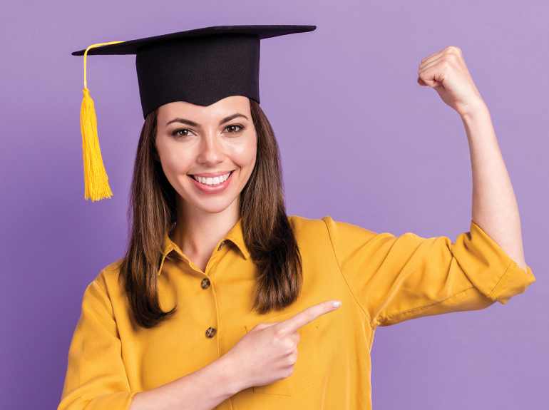 Woman wearing graduation cap, flexing arm muscle