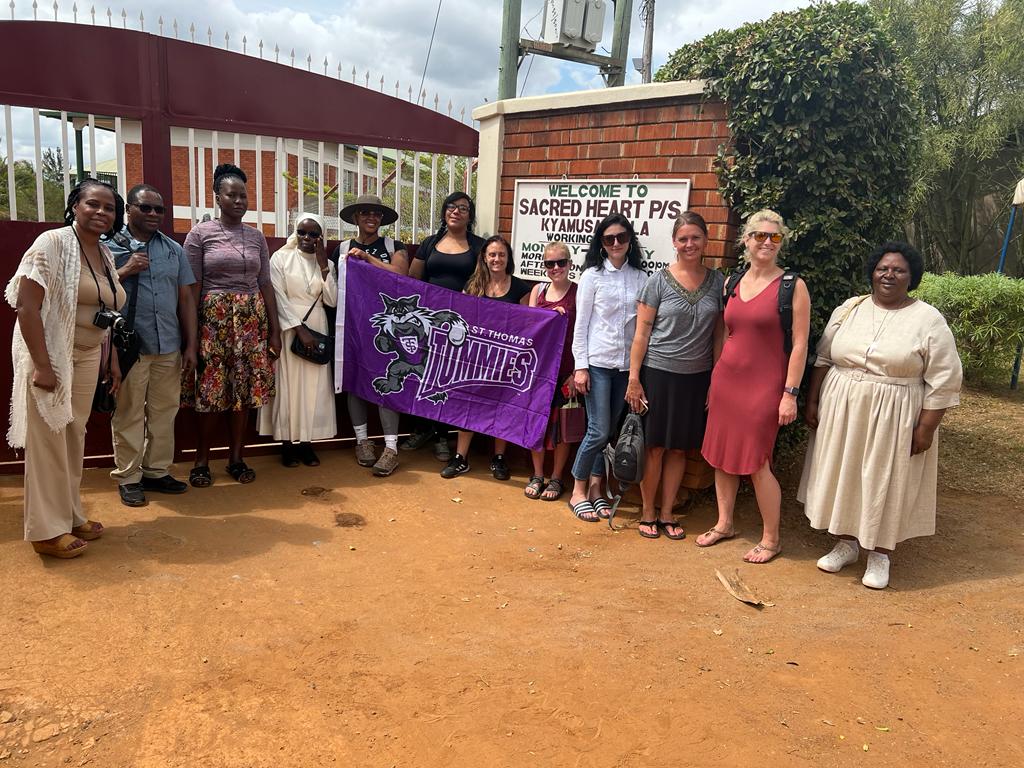 Group of St. Thomas students in Uganda holding a Tommie banner